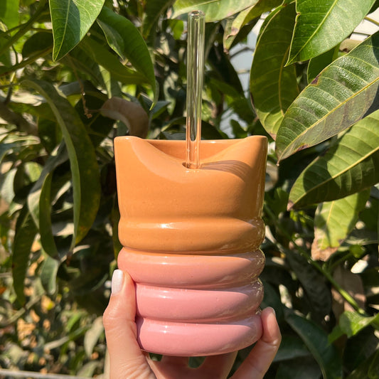 Close-up of handmade pottery tumbler in peach glow ceramic glaze with artisanal details.”