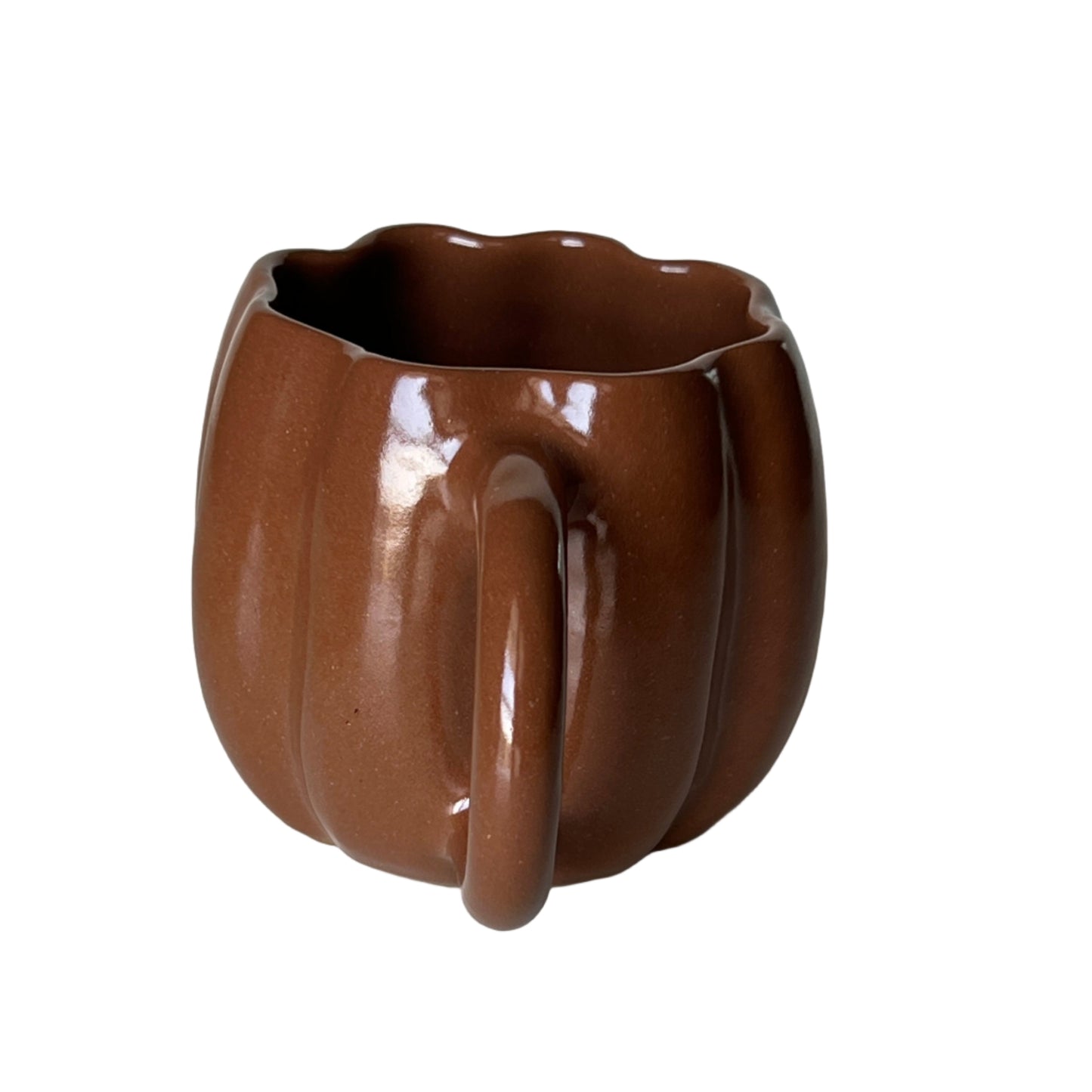 Brown ceramic cup with a unique handle design on a light gray surface.
