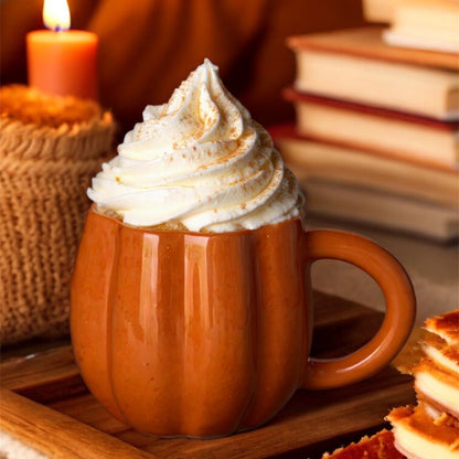 Pumpkin mug with whipped cream, candles, and books in the background