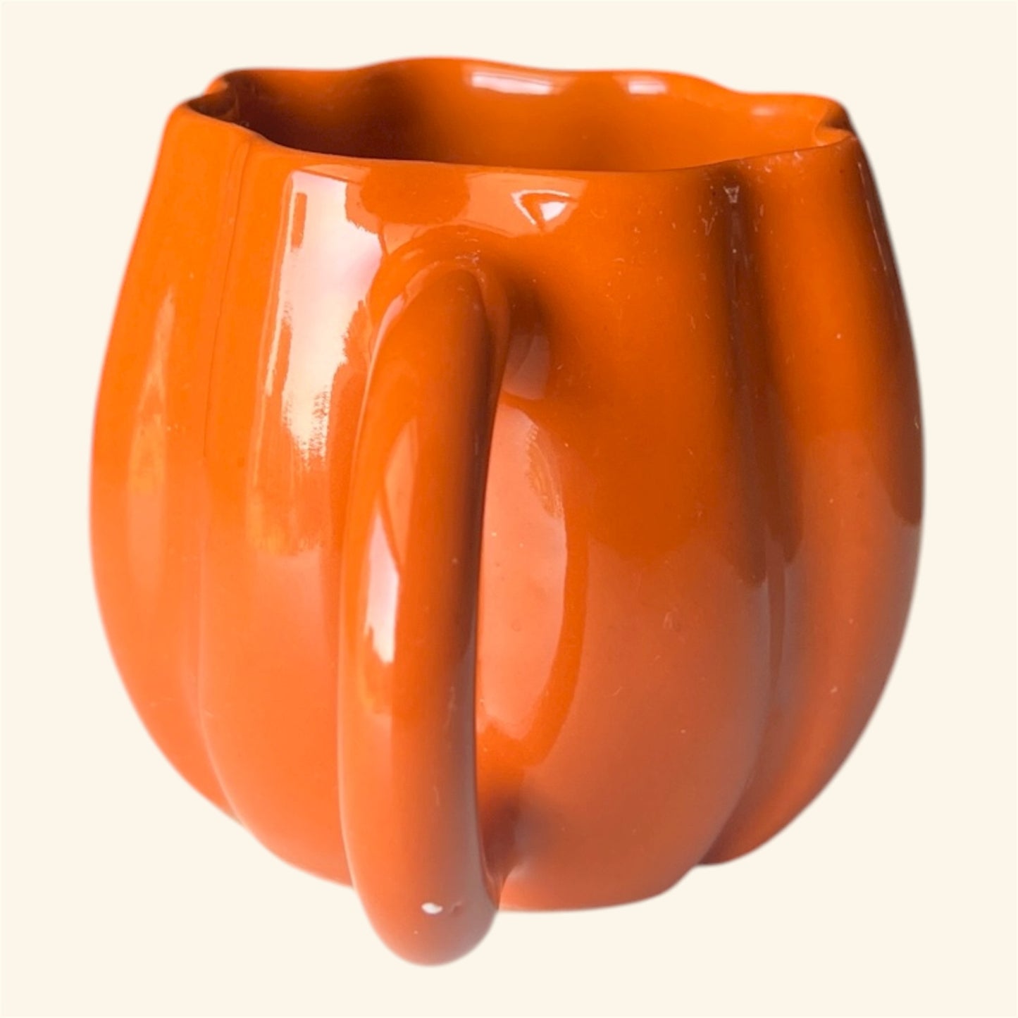 Orange ceramic mug with a unique handle design on a white background